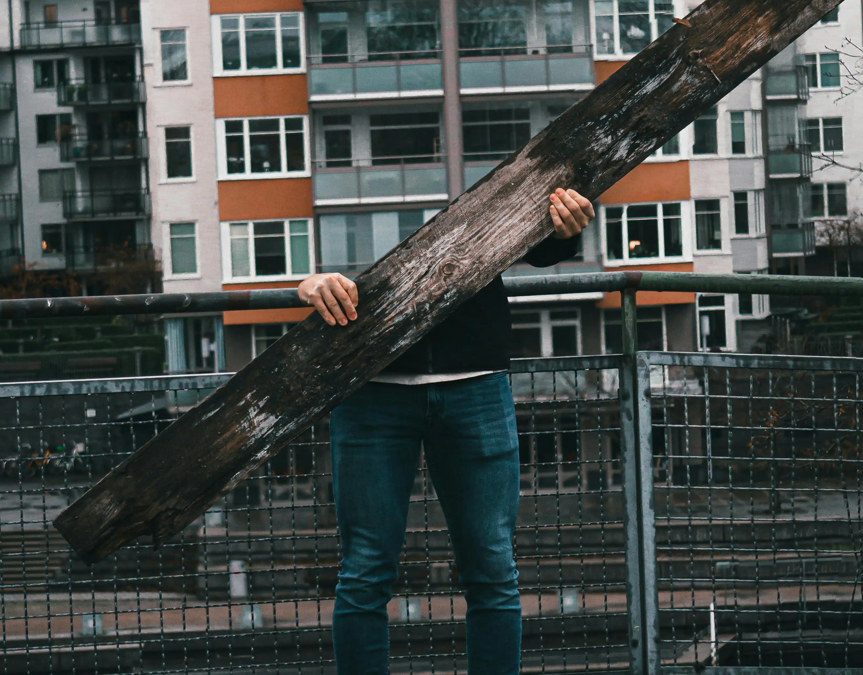 A man with an invisible torso holding a wooden plank.